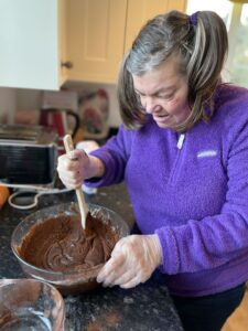 A supported holiday guest mixes brownie batter